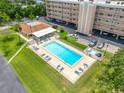 Overhead view of a community pool with lounge chairs and clubhouse, set in a grassy, fenced area at 9450 Harbor Greens Way # 207, Seminole, FL 33776
