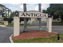 Community entrance with an Antigua sign, palm trees and well maintained grounds at 9700 Starkey Rd # 325, Seminole, FL 33777