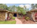 Inviting front entrance with stone accents, a brick path, lush landscaping, and comfortable seating on the porch at 1025 Reading Rd, Lutz, FL 33558