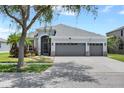 Inviting single-story home showcasing a three-car garage, screened entry, and landscaped front yard at 13336 Graham Yarden Dr, Riverview, FL 33579