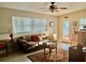 Cozy living room featuring a brown leather couch, ceiling fan, and natural light from large windows at 14530 Apache Ave, Largo, FL 33774