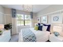 Stylish bedroom with decorative lighting, patterned curtains, white furniture, and a bed with blue accents at 15021 Oxford Grey Dr, Lakewood Ranch, FL 34211