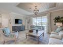 Cozy living room with stylish furnishings, a decorative ceiling, and sliding glass doors to the lanai at 15135 Oxford Grey Dr, Bradenton, FL 34211