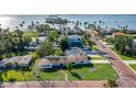 Stunning aerial view of coastal homes with manicured lawns and views of the bay in the distance at 1794 Santa Barbara Dr, Dunedin, FL 34698