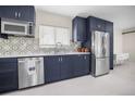 Modern kitchen with stainless steel appliances, dark blue cabinets, and stylish backsplash at 1794 Santa Barbara Dr, Dunedin, FL 34698