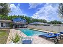 Beautiful pool area with brick pavers, lounge chairs, and lush landscaping, perfect for outdoor relaxation at 1902 Rebecca Rd, Lutz, FL 33548