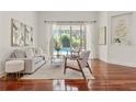 Sunlit living room boasts hardwood floors, modern decor, and a tranquil view of the pool at 2901 Laurel Meadow Ct, Plant City, FL 33566