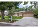 Beautifully landscaped front yard with mature trees, lush lawn, and charming home exterior at 3821 Turkey Oak Dr, Valrico, FL 33596