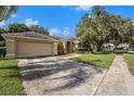 Tan home with a two car garage and mature landscaping, creating a welcoming curb appeal at 4303 Kipling Ave, Plant City, FL 33566