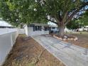 Quaint home showcasing a well-kept lawn, mature tree, and a white picket fence enhancing the property's perimeter at 5175 88Th N Ave, Pinellas Park, FL 33782