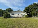 Cozy single-story home with a lush, green lawn, mature trees, and a classic carport at 5600 9Th N Ave, St Petersburg, FL 33710
