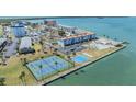 An aerial view of a waterfront community featuring tennis courts, a pool, and surrounding residences at 7 Elgin Pl # 202, Dunedin, FL 34698