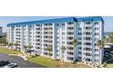 Exterior shot of a multi-story condo building with white balconies and tropical landscaping at 7 Elgin Pl # 202, Dunedin, FL 34698