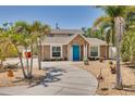 Charming home with a blue front door, stone accents, landscaped yard, and a curved driveway with palm trees at 941 65Th S St, St Petersburg, FL 33707