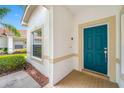 Welcoming home entrance featuring a teal front door, neutral trim, and brick paver landing at 10255 Devonshire Lake Dr, Tampa, FL 33647