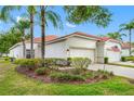 Beautiful white home with a red tile roof, complemented by lush landscaping and mature palm trees at 10255 Devonshire Lake Dr, Tampa, FL 33647