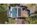 Aerial view of a home with a screened pool, solar panels, and a deck overlooking the water at 12416 Queensland Ln, Tampa, FL 33625