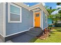 Close-up of a charming home's entrance featuring a decorative orange front door and freshly landscaped yard at 13325 1St E St, Madeira Beach, FL 33708