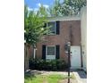 Charming brick townhome featuring black shutters, a white door, a green lawn, and mature landscaping at 13709 Juniper Blossom Dr, Tampa, FL 33618
