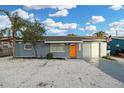 Charming single-story home with a vibrant orange front door and a well-maintained, light gray exterior at 13800 Judy Ave, Hudson, FL 34667