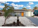 Charming single-story home with a vibrant orange front door and a well-maintained, light gray exterior at 13800 Judy Ave, Hudson, FL 34667