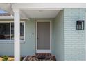 Charming front entrance with light blue brick, white trim, and a welcoming welcome mat at 15713 Century Dr, Hudson, FL 34667