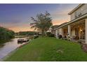 Manicured backyard with a lake view, dock, lush green lawn, and a covered patio at 18050 Cozumel Isle Dr, Tampa, FL 33647