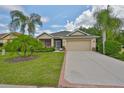 Inviting single-Gathering home features a lush front lawn, palm trees, and a screened-in porch for relaxing outdoors at 2128 Worthington Greens Dr, Sun City Center, FL 33573
