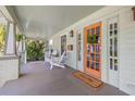 Inviting front porch with a painted floor and an orange front door featuring decorative wreath and sidelights at 3114 W Granada St, Tampa, FL 33629