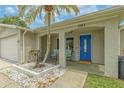 Inviting front porch featuring a blue door, neutral paint, and manicured landscaping at 3145 Domino Dr, Holiday, FL 34691