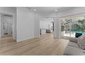 Bright and airy living room featuring wood flooring, neutral walls, and a view of the pool through sliding glass doors at 403 Carriage House Ln, Tarpon Springs, FL 34688