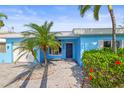 Inviting home featuring a well-maintained front yard, a paver walkway leading to a covered entrance, and lush landscaping at 403 Normandy Rd, Madeira Beach, FL 33708