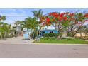Charming single-story home with fresh blue paint, complemented by a manicured lawn and mature flowering tree at 403 Normandy Rd, Madeira Beach, FL 33708