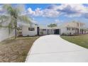 A well maintained white brick home featuring professional landscaping and a bright driveway at 6304 Memorial Hwy, Tampa, FL 33615