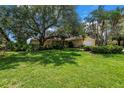Well-manicured front yard showcasing a lush lawn, mature trees, and a charming home exterior with great curb appeal at 8127 Siquita Ne Dr, St Petersburg, FL 33702