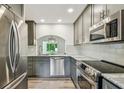 Modern kitchen features stainless steel appliances, gray cabinets, and stone countertops at 11628 Aspenwood Dr, New Port Richey, FL 34654
