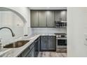 Kitchen featuring stainless steel appliances, gray cabinets, and luxurious marble countertops at 11628 Aspenwood Dr, New Port Richey, FL 34654