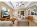 Comfortable living room with neutral walls, tile floors, tray ceiling, and open access to the kitchen bar at 11813 Crawford Parrish Ln, Parrish, FL 34219