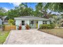 Charming light-blue home with well-manicured lawn, stone pathway, and inviting front porch area at 1213 E Idlewild Ave, Tampa, FL 33604
