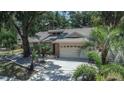 A single-story home with tropical landscaping, an attached garage and mature trees at 1613 Long Pond Dr, Valrico, FL 33594