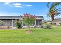 Lovely home exterior featuring mature trees, flowering bushes, and a screened-in patio at 1802 Bedford Ter # 185, Sun City Center, FL 33573