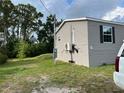 The side of the house is clad in gray siding, showing a AC electrical system and a green lawn at 3221 Roxborough Ave, Clearwater, FL 33762