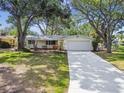 Attractive single-story home with a well-maintained lawn, mature trees, and a concrete driveway leading to the garage at 5825 Oakhurst Dr, Seminole, FL 33772