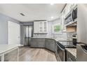 Well lit kitchen features stainless steel appliances, stone countertops, and grey wood flooring at 10537 Fran St, New Port Richey, FL 34654