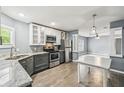Well lit kitchen features stainless steel appliances, stone countertops, and grey wood flooring at 10537 Fran St, New Port Richey, FL 34654