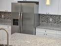 Spacious kitchen featuring stainless steel refrigerator, granite countertops, and a tiled backsplash for a modern look at 11210 Mcmullen Rd, Riverview, FL 33569