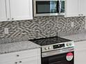Close-up of a kitchen with stainless steel appliances, granite countertops, and stylish backsplash detailing at 11210 Mcmullen Rd, Riverview, FL 33569