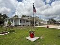 Charming single-story home featuring a long driveway, carport, and manicured lawn under a partly cloudy sky at 12021 Club House Rd, Brooksville, FL 34613
