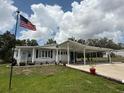 Charming single-story home featuring a long driveway, carport, and manicured lawn under a partly cloudy sky at 12021 Club House Rd, Brooksville, FL 34613
