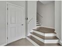 A modern entryway with neutral tones, a white paneled door, and the bottom portion of a stairway leading to the upper floors at 1402 Harbour Walk Rd, Tampa, FL 33602